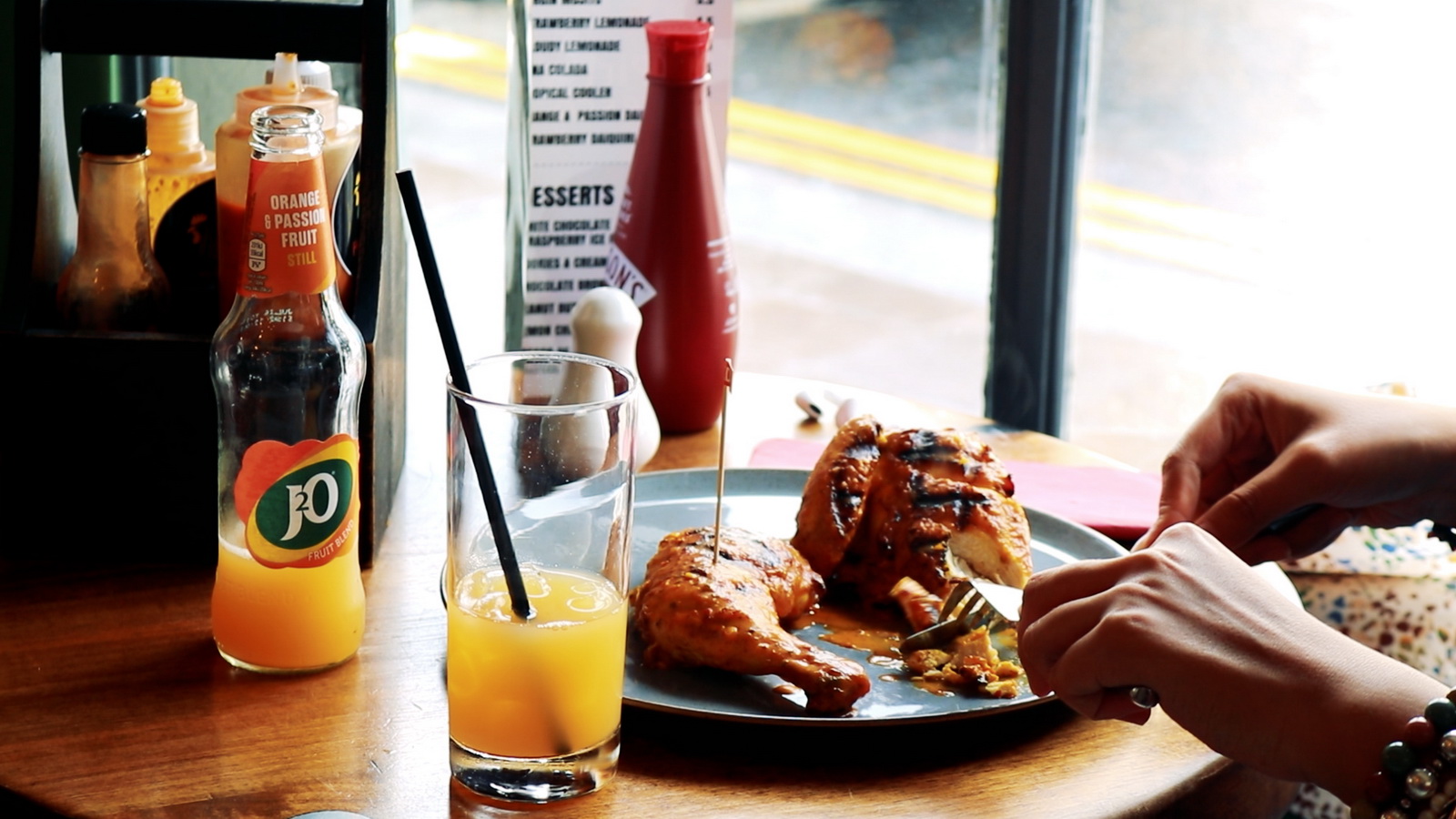 Flame-grilled half chicken being tucked into at a window table